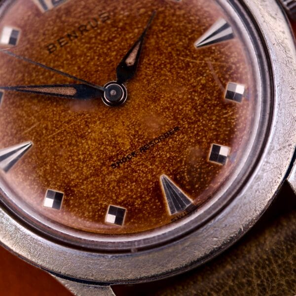 Close-up of the Benrus Shock-Absorber Tropic Dial Silver Indicies wristwatch, featuring a textured brown dial, silver hour markers and hands, and built-in shock-absorption for durability.