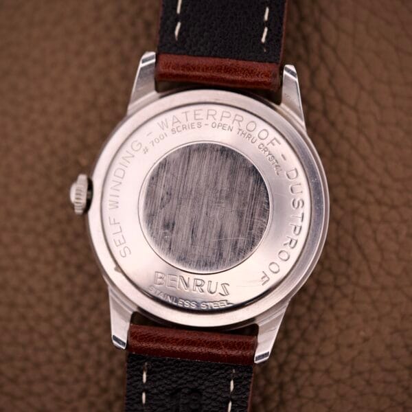 A close-up of a Benrus Three Star Automatic Day-Date Sunburst Dial #7001 Series watch back, showing engraved details and a scratched central area.