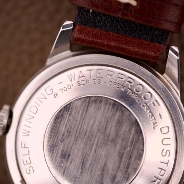 Close-up of a Benrus Three Star Automatic Day-Date Sunburst Dial #7001 Series watch back engraved with WATERPROOF, DUSTPROOF, and OPEN THRU CRYSTAL.