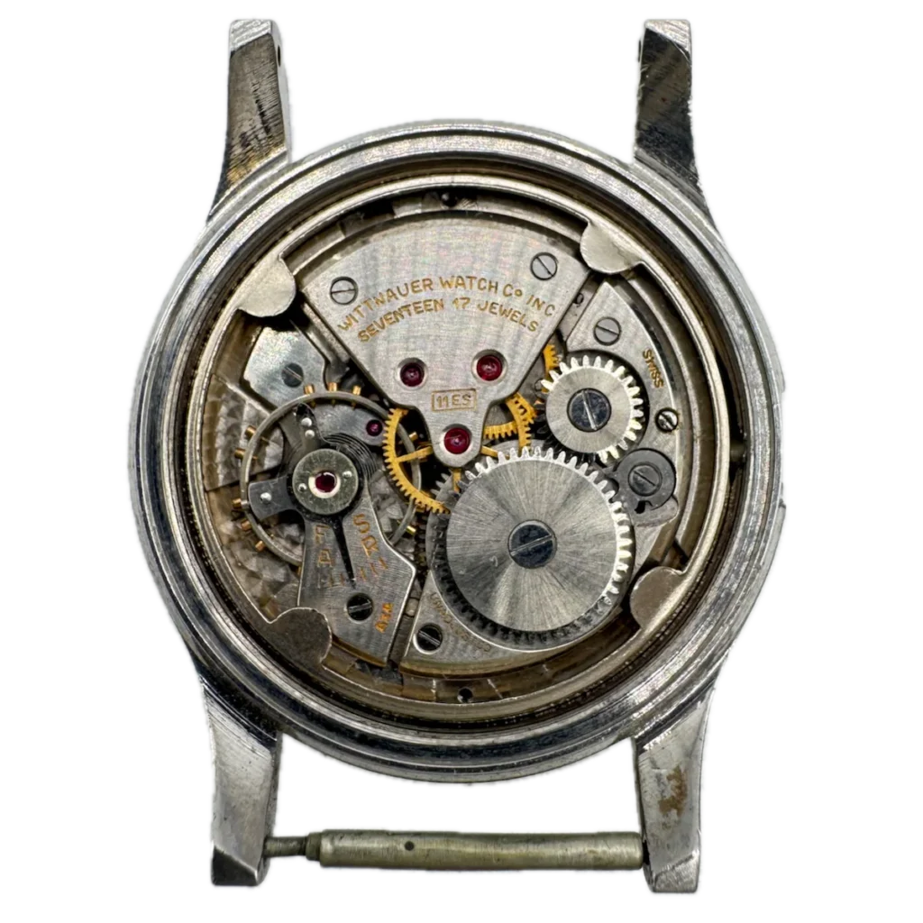 Close-up of a vintage Wittnauer 11ES watch movement, showcasing its visible gears and intricate metal parts.