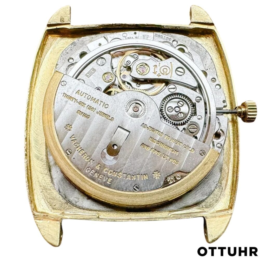 Close-up of a Vacheron Constantin k1121 watch movement inside a gold case, displaying intricate gears and detailed markings.