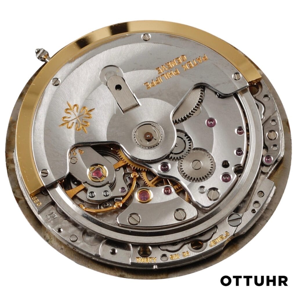 Close-up of a luxury watch movement, showcasing the intricate gears and metal parts of the Patek Philippe 28-255 C caliber, labeled Patek Philippe.