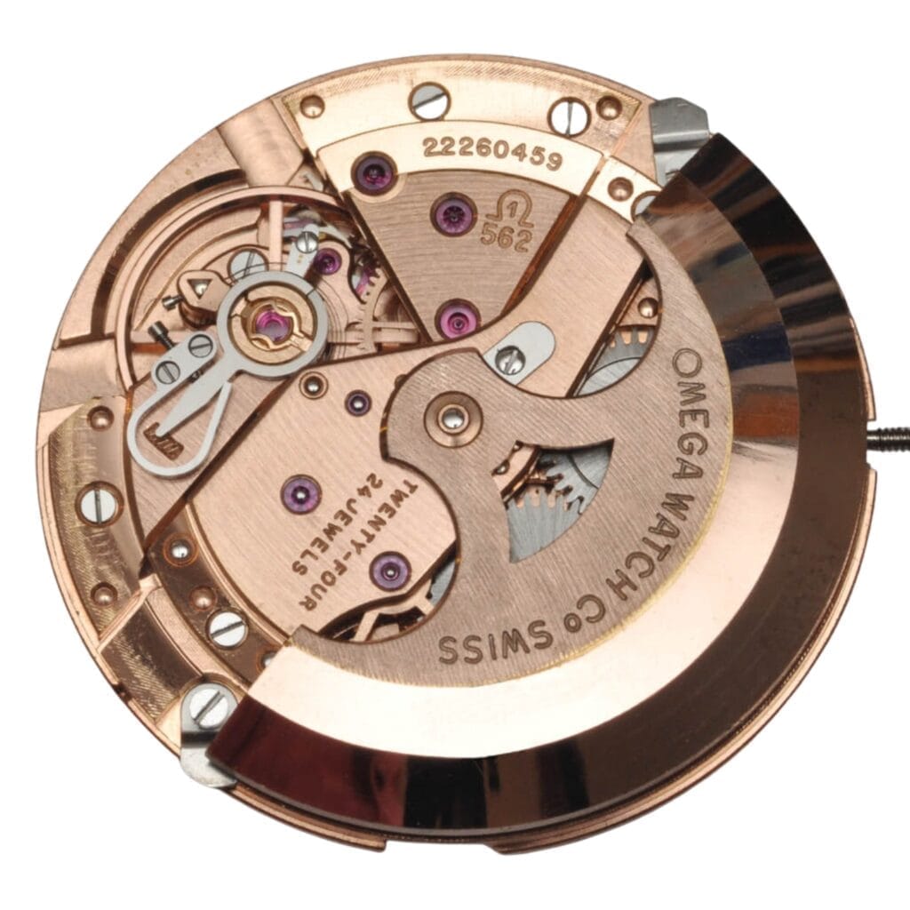Close-up of an Omega 562 watch movement, showcasing detailed gears, screws, and engraved text on rose gold-colored metal.