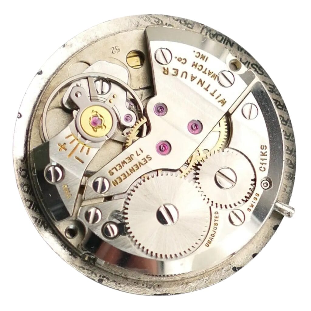 Close-up of a vintage Wittnauer C11KS mechanical watch movement with visible gears, screws, and engraved markings.