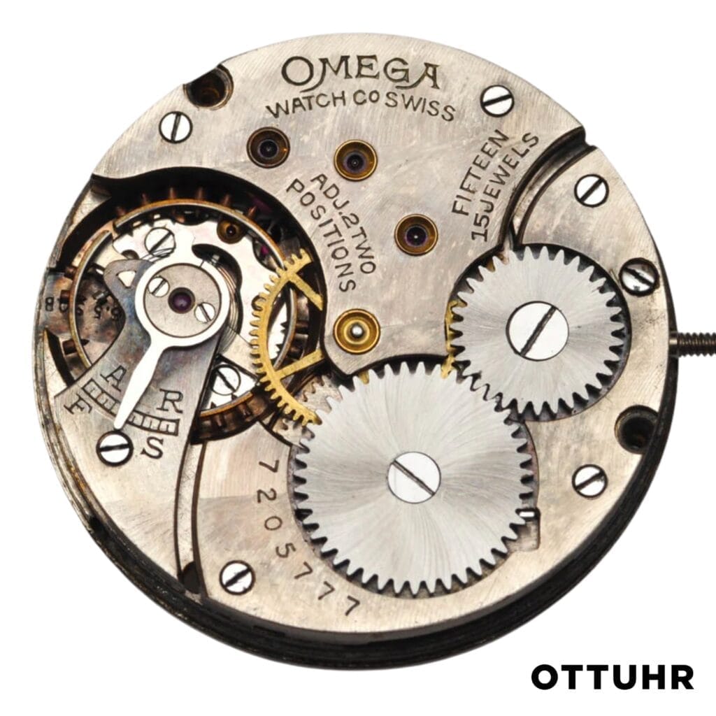 Close-up of an Omega 26.5 watch movement showing intricate gears, jewels, and engraved markings on the metal surface.