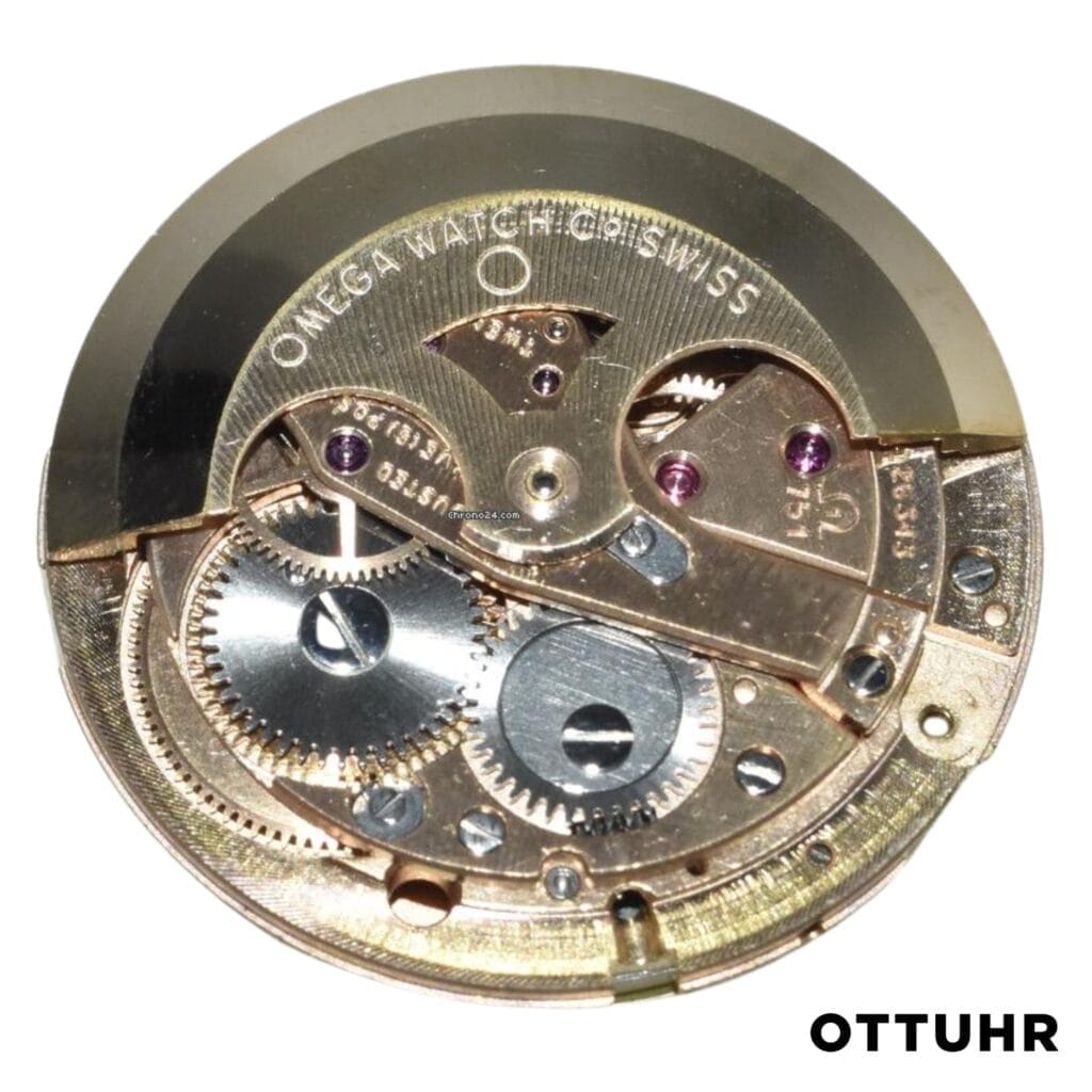 Omega 751 watch movement mechanism with visible gears, screws, and engraved text, viewed from above.
