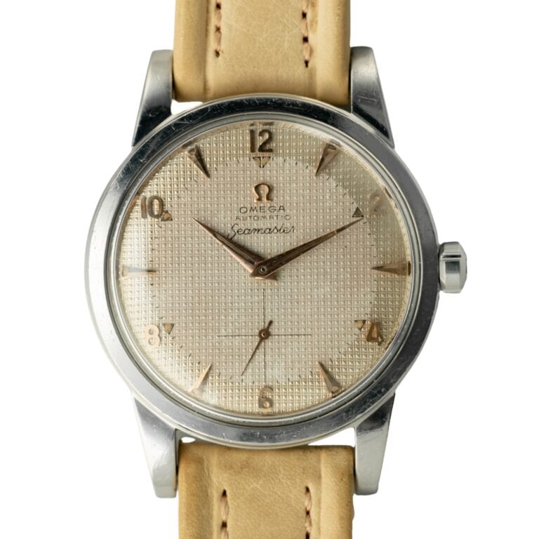 Close-up of a vintage Omega Seamaster CK 2494 watch with a beige leather strap and textured dial.