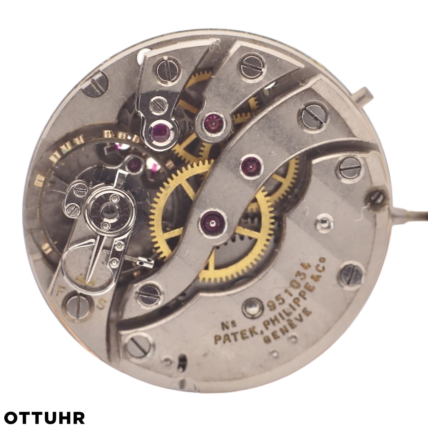 Close-up of a Patek Philippe 10-200 watch movement, highlighting intricate gears, screws, and engraved text on metal.