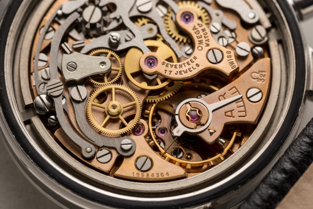 Close-up of an intricate Omega Seamaster 105.001 watch movement, showcasing golden gears, screws, and finely crafted metal components.