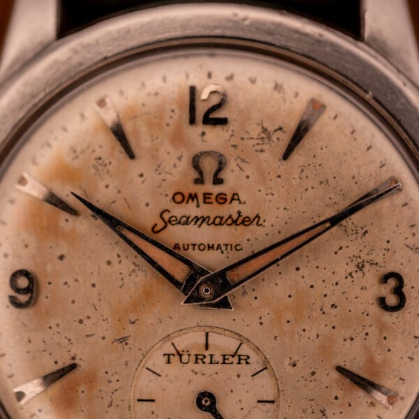 Macro close-up of Omega Seamaster Türler signed dial showing freckled cream patina and dauphine hands