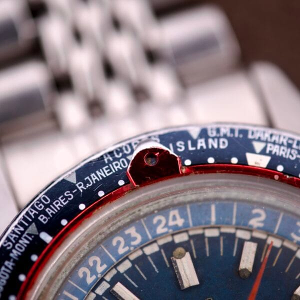 Close-up of the Enicar Sherpa Guide 600 "Pepsi" Automatic World Timer GMT Ref. 2342 bezel, displaying city names like Santiago and Rio de Janeiro with a bold blue and red design.