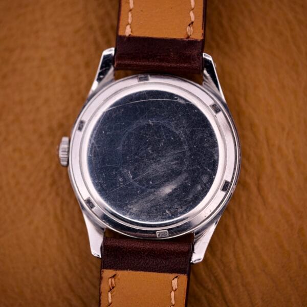 An Omega Jumbo Ref. 2640 Manual Wind Cal. 283 with a "Türler" dial, blank and scratched face, and brown leather strap is displayed against a tan background.