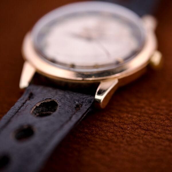 Close-up of a Zodiac Glorious Automatic Tuxedo Dial Ref. 688 Cal. 1361 wristwatch with black perforated leather strap, resting on a brown surface.