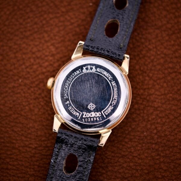 A close-up of the back of a Zodiac Glorious Automatic Tuxedo Dial Ref. 688 Cal. 1361 wristwatch with a black leather strap resting on brown leather.