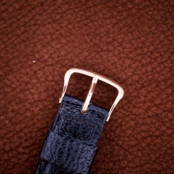 Close-up of a black leather strap with a gold buckle on the Zodiac Glorious Automatic Tuxedo Dial Ref. 688 Cal. 1361, set against a textured brown background.