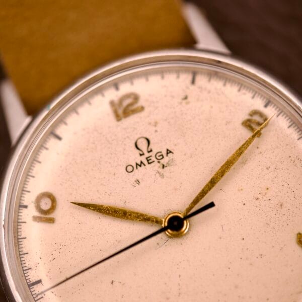 Close-up of an Omega Ref. 2338 Jumbo wristwatch featuring gold hands, a tan leather strap, and a stainless steel case with Caliber 30T2 SC movement.