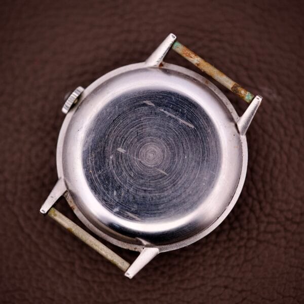 Omega Ref. 2338 Jumbo Stainless Steel Case Caliber 30T2 SC with a scratched back, no strap, and visible wear, shown on a textured brown surface.