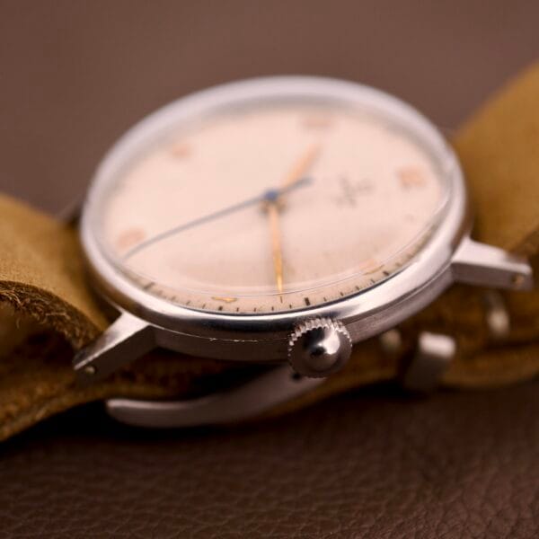Close-up of an Omega Ref. 2338 Jumbo with Caliber 30T2 SC, featuring a stainless steel case and leather strap, displayed on a brown surface.