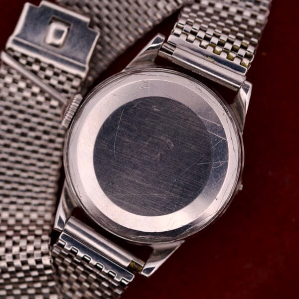 A close-up of the Movado Automatic Date Ref. 16291 watch features a stainless steel mesh band and shows the scratched back of its Bumper Cal. 224A case.
