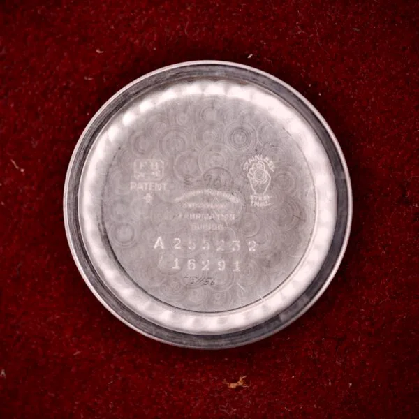 A round stainless steel case back from a Movado Automatic Date Ref. 16291 Bumper Cal. 224A, with Cal. 224A engravings, rests on a red textured surface.