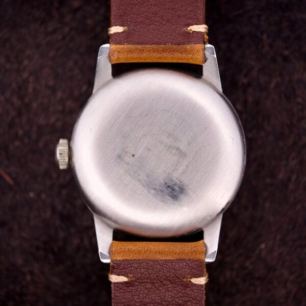 A close-up of the Omega Ref. 2496 Arabic Numerals with stainless steel case and brown leather strap, showcasing Cal. 30T2 SC details against a dark background.