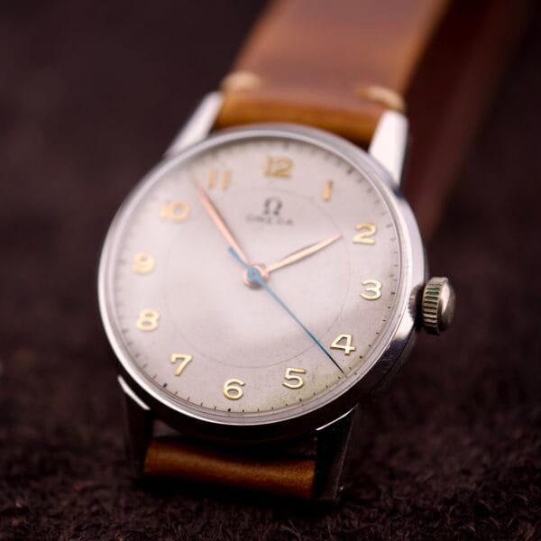 Close-up of an Omega Ref. 2496 with Arabic numerals, a stainless steel case, Cal. 30T2 SC movement, and a brown leather strap.