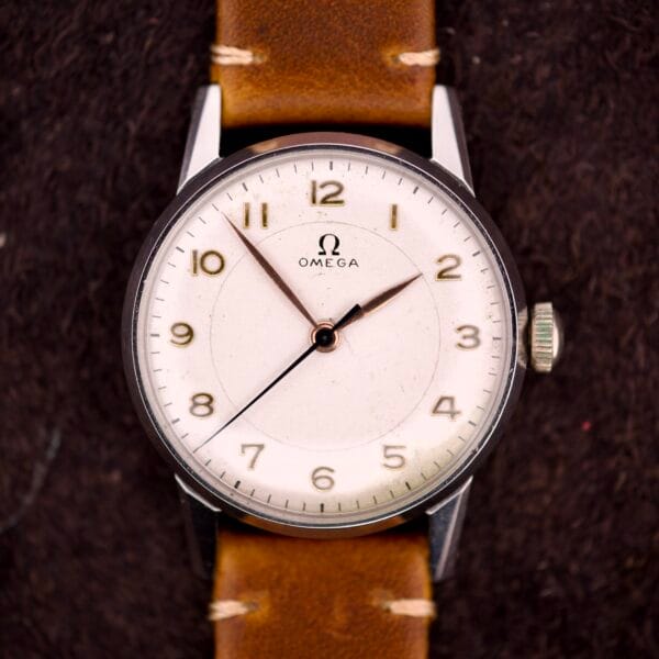 An Omega Ref. 2496 with Arabic numerals, stainless steel case, brown leather strap, white dial, silver markers, and Cal. 30T2 SC movement displayed on a dark background.