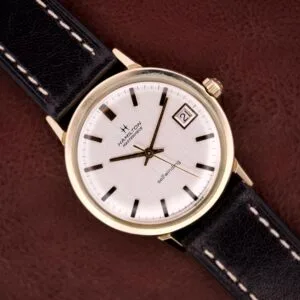 Hamilton Masterpiece Self-Winding Date wristwatch with 10K gold-filled case, white dial, black markers, date window, Cal. 822 movement, and black leather strap.
