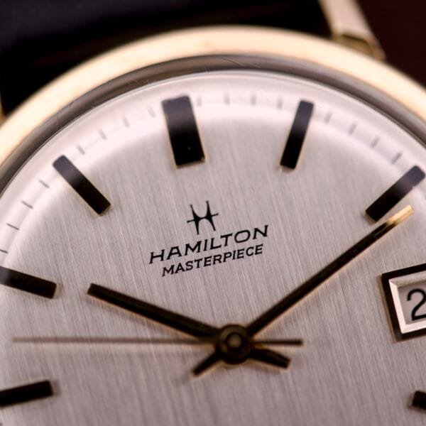 Close-up of the Hamilton Masterpiece Self-Winding Date in 10K GF Case Cal. 822, highlighting its date feature, elegant hands, markers, and part of the gold-filled case.