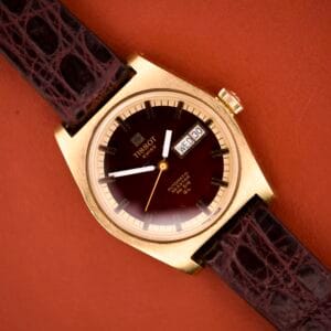 A vintage Tissot Seastar PR 516 GL (Ref. 46572) with maroon dial, gold case, brown leather strap, and day/date display (Cal. 794).