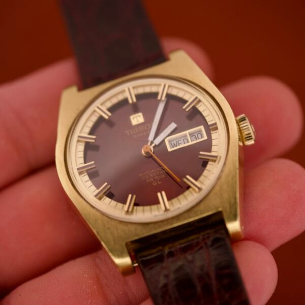A hand holds the Tissot Seastar PR 516 GL Maroon Dial Ref. 46572, featuring a day/date display and leather strap.
