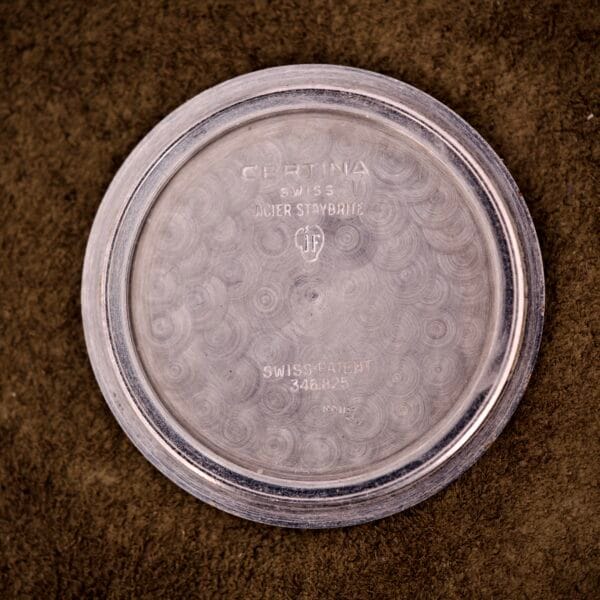 Certina DS Ref. 346.825 1st Gen Cal. 25-36 stainless steel case back with engraved text, shown on a brown textured surface.