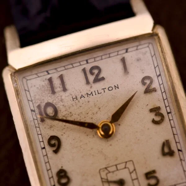 Close-up of the Hamilton Tank 14k Gold Filled Case Manual Wind Cal. 982 U.S.A., a vintage wristwatch with a rectangular, worn dial showing 1:48, classic manual winding movement, and elegant gold-filled case.