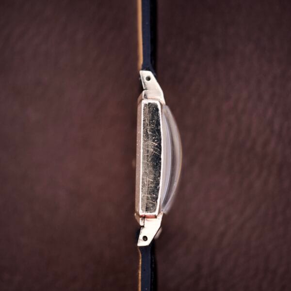 Close-up top view of a Hamilton Tank 14k Gold Filled Case Manual Wind Cal. 982 U.S.A. wristwatch with a leather strap on a brown surface.