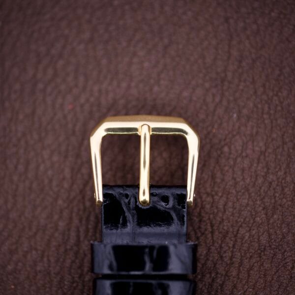 Hamilton Tank 14k Gold Filled Case Manual Wind Cal. 982 U.S.A. watch with a black leather strap, shown on a brown textured surface.