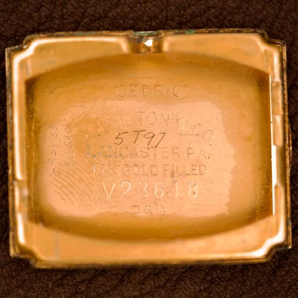The Hamilton Tank 14k Gold Filled Case Manual Wind Cal. 982 U.S.A. features a gold-colored case back engraved with Hamilton Watch Co., 14K Gold Filled, V23618, Cedric, and other vintage hallmark details.
