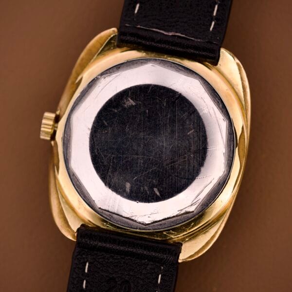 A close-up of the back of a vintage Tissot Automatic Seastar Day/Date with a worn metal case and black leather strap, featuring the Cal. 2571 movement and a brown ombre dial.