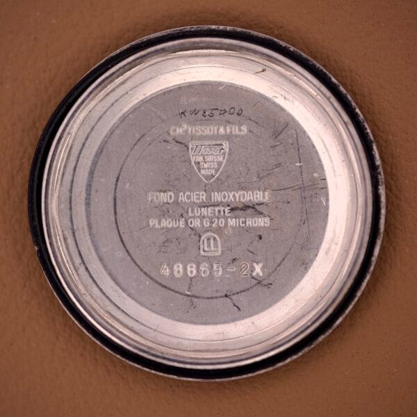 The inside case back of a Tissot Automatic Seastar Day / Date Brown Ombre Dial Cal. 2571 watch displays engraved text and numbers on its metallic surface.