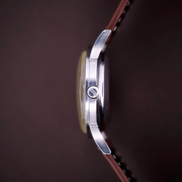 Close-up side view of a 1959 Bulova Self-Winding Cal. 11AFAC with fancy lugs, leather strap, and stainless steel case, shown against a dark background.