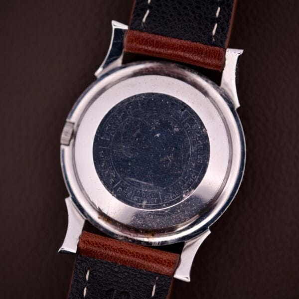 Back view of the 1959 Bulova Self-Winding Cal. 11AFAC with fancy lugs, featuring a brown and black leather strap and engraved markings on its stainless steel case.