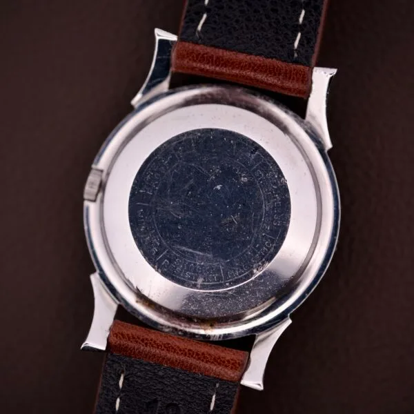 Back view of the 1959 Bulova Self-Winding Cal. 11AFAC with fancy lugs, featuring a brown and black leather strap and engraved markings on its stainless steel case.