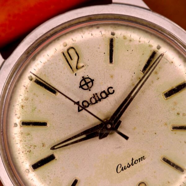 Close-up of a vintage Zodiac Hermetic Custom Manual Wind watch, highlighting its stainless steel case, hands, logo, and visible aging marks.