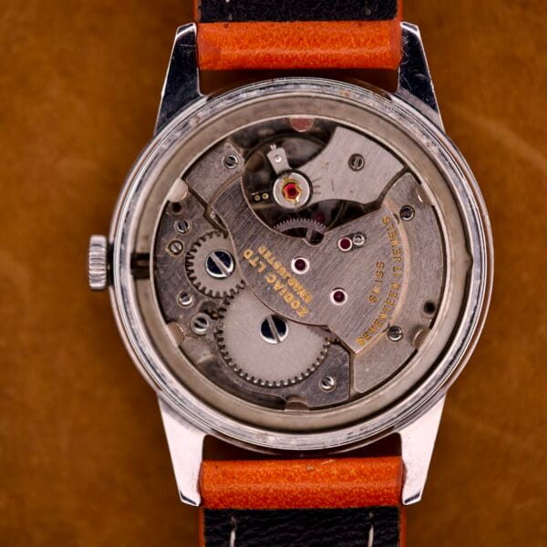 Close-up of the Zodiac Hermetic Custom Manual Wind’s exposed mechanical movement, revealing visible gears and metal parts inside its stainless steel case.