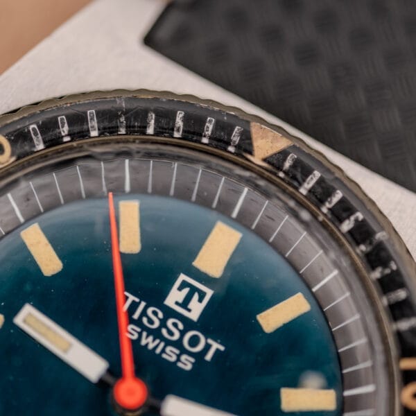 Close-up of a Tissot PR-516 "Roger Moore" Balkelite Bezel Ref. 44622 wristwatch face with luminous hands and indices, showing part of the signature Balkelite bezel.