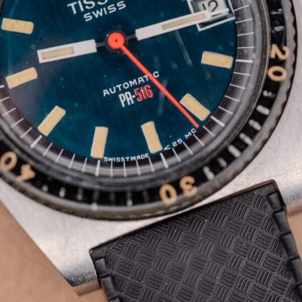 Close-up of the Tissot PR-516 "Roger Moore" Balkelite Bezel Ref. 44622, showcasing its distinctive hands, numerals, and part of the black strap—a classic design once favored by Roger Moore.