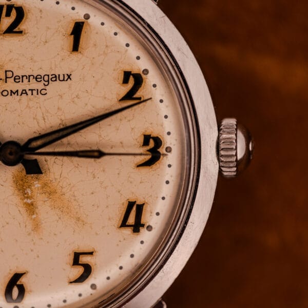 Close-up of a Girard Perregaux Gyromatic in Stainless Steel with Arabic numerals dial, showing 8:14. The watch features visible aging on its worn dial and a classic vintage case.