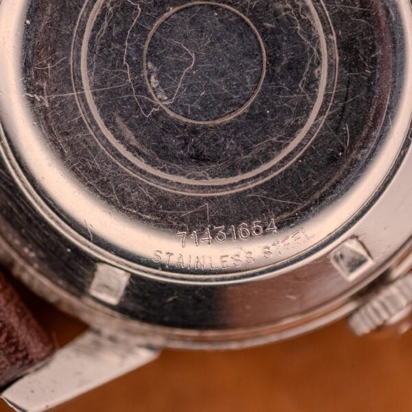 Close-up of a scratched stainless steel Girard Perregaux Gyromatic in Stainless Steel Arabic Numerals Dial watch back, displaying the serial number 71431654.
