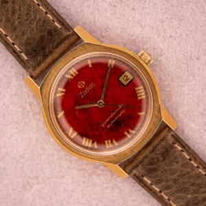 The Zodiac Guardsman Automatic Burgundy Lacquered Dial Ref. 723-950 B features a gold case, brown leather strap, and Roman numerals.