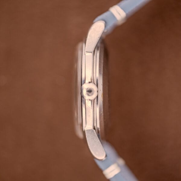 Side view of an Omega Seamaster Automatic Tropic Dial Ref. 2848 Cal. 490 silver watch with blue straps shown on a brown background.