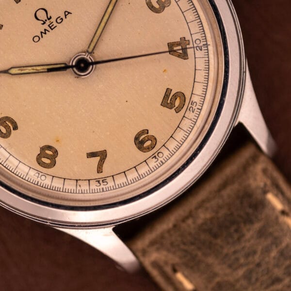Close-up of an Omega WWII Era Military "US ARMY" Ref. 2179 Cal. 30T2 SC wristwatch in stainless steel, featuring a beige dial and brown leather strap.